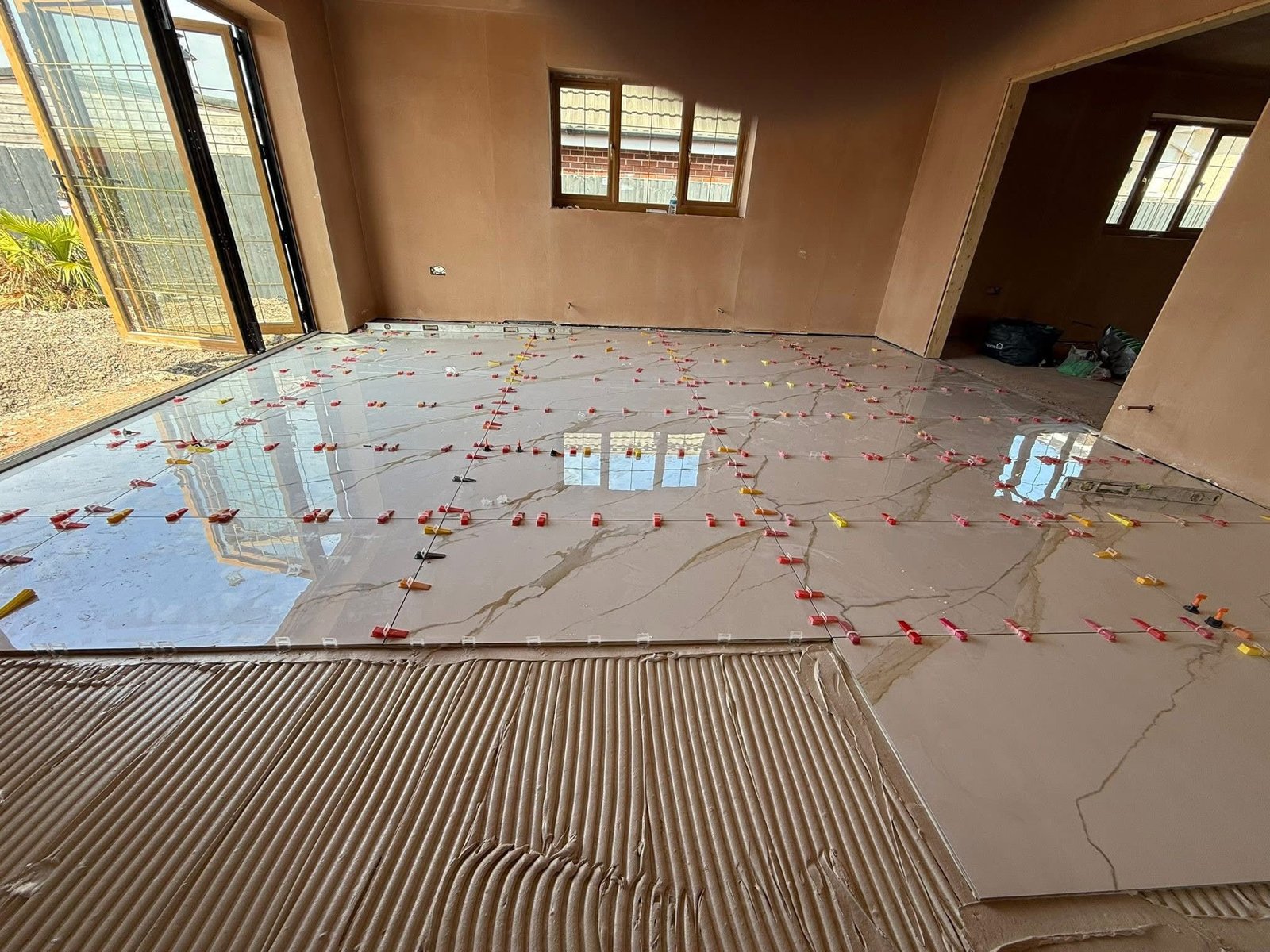 Large floor tiles being laid with levelling clips