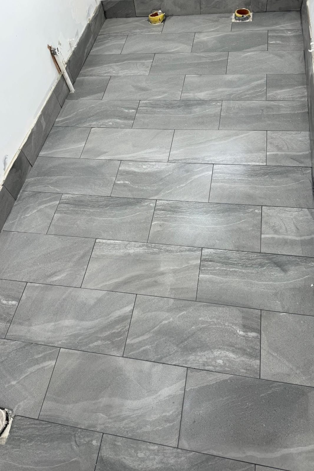 Grey stone-effect floor tiles in a brick pattern fitted by SN&J Construction
