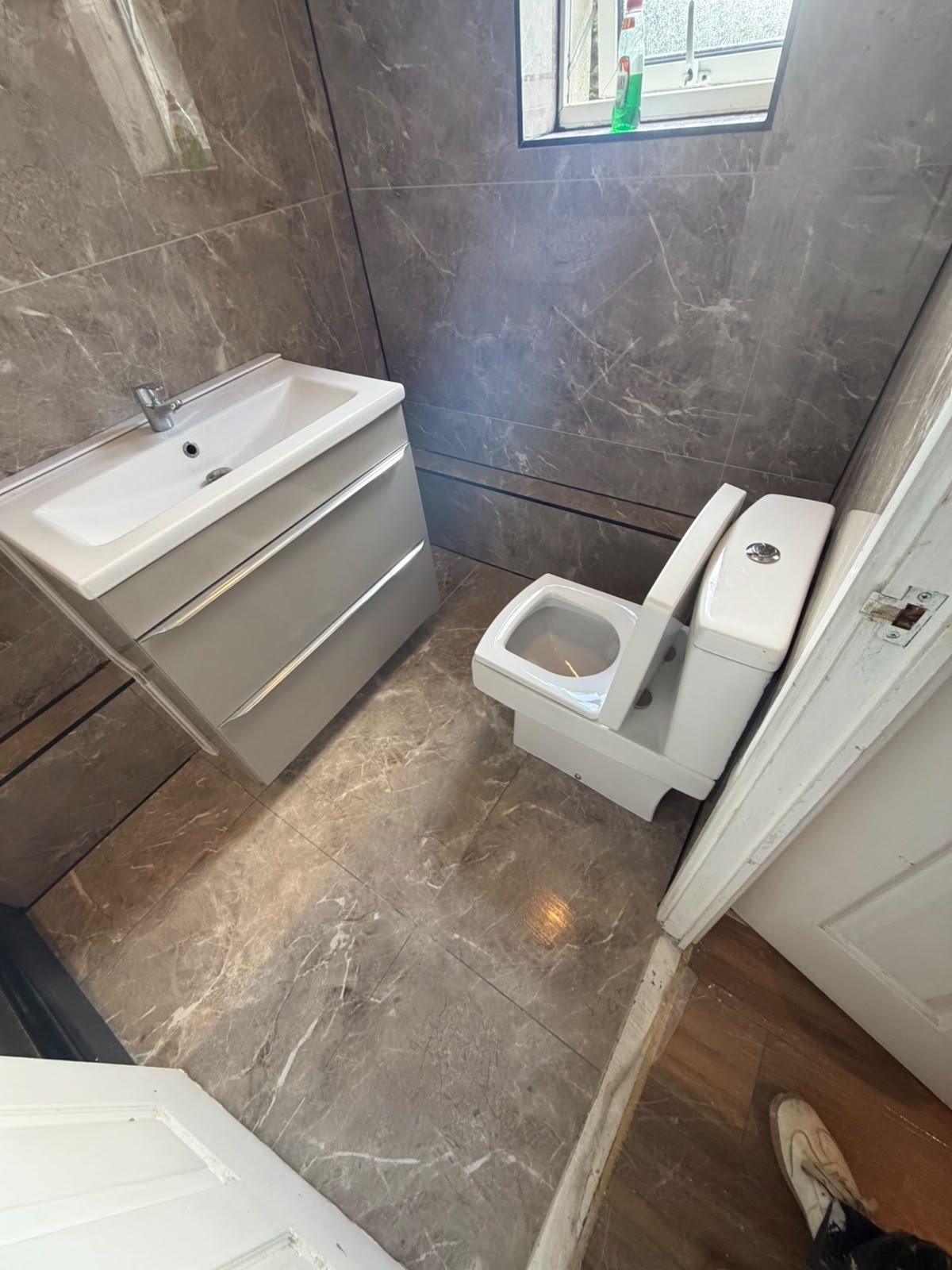 Marble-effect tiled bathroom with vanity and toilet