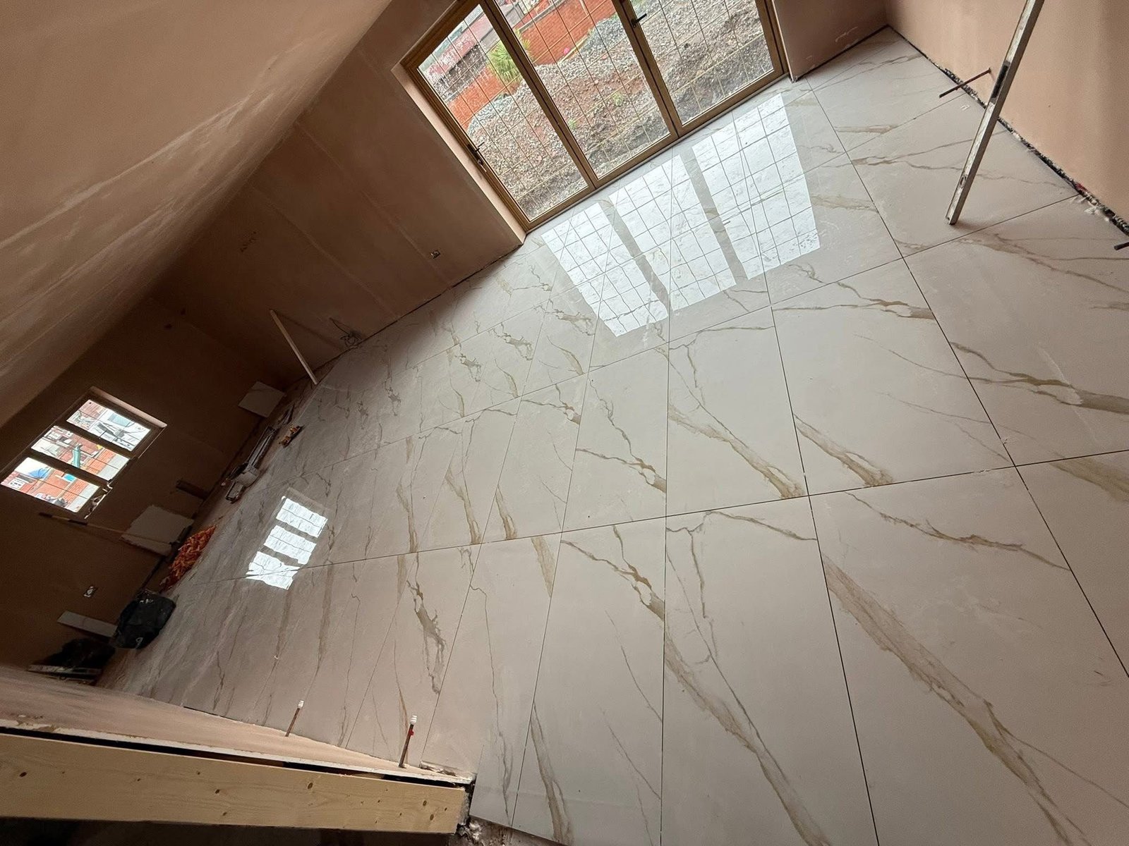 Large-format marble-effect floor tiles laid in an open room by SN&J Construction